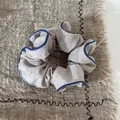 Primo piano di uno scrunchie a pois con bordi arricciati blu su un panno di lino. - Stile a Pois Cachi