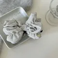 Dettaglio di una clip a banana a fiocco a pois bianchi su un vassoio in ceramica - Stile Pois Beige