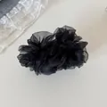 Vista detallada de un elegante clip de banana de malla negra con pliegues florales - Clip de Plátano con Volantes / Negro