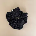 Detail van de fijne stoftextuur en het witte stippenpatroon van deze zwarte scrunchie - Zwarte Polka Dot Scrunchie
