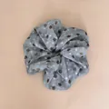 Close-up van een retro grijze scrunchie met bruine stippen en elegante stoftextuur. - Blauwe gestippelde scrunchie