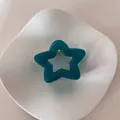 Vista detallada de una pinza para el pelo con forma de estrella en plato blanco - Estrella Plateada / Azul lago