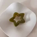 Primer plano de una pinza para el pelo minimalista verde oliva con forma de estrella - Estrella Plateada / Verde