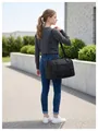 Vue détaillée d'un grand sac de voyage noir porté par un mannequin dans un cadre extérieur - Taille unique / Noir