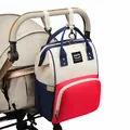 Detail van de multifunctionele luiertas rugzak bevestigd aan een kinderwagenstang - Rood Milaan Mix