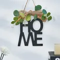 Vista detallada de una decoración de pared HOME de madera con hojas verdes y lazo - Negro