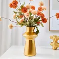 Modern golden lighthouse-shaped resin vase with vibrant orange faux flowers for home decor - Gold