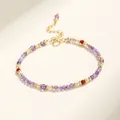 Primer plano de una elegante pulsera de amatista púrpura y cuentas doradas sobre fondo claro - Amatista
