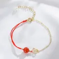 Feines Armband mit roter Kordel und Goldkette mit roter Perle und Blumenanhänger - Chinesisches Knoten-Design / Roter Achat