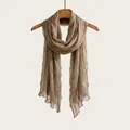 Lightweight taupe pleated cotton linen scarf displayed on a wooden hanger. - Dark Camel