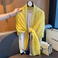 Detail view of a yellow leaf print scarf with tassels styled in a lifestyle setting. - 180cm / Yellow Blue Block
