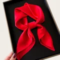 Close-up of elegant red silk square scarf tied in a knot inside a black box - 68cm / Red
