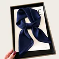 Detailed view of an elegant dark blue silk scarf bow on a white magazine in a box - 68cm / Navy Blue