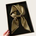 Close-up detail of elegant bronze silk square scarf tied in a gift box for neck styling. - 68cm / Brown