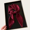 Elegant burgundy silk-like square neck scarf tied in a bow on a black display tray. - 68cm / Burgundy