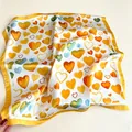 Vista dettagliata dei motivi a cuore colorati su un foulard quadrato di finta seta da 70cm. - 70cm / Giallo