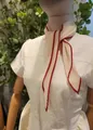Detailopname van een crème geplooide skinny sjaal met decoratieve rode geschulpte randen - gebroken wit met rode rand