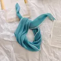 Detailopname van een lichtblauwe geplooide sjaal met witte zigzag borduursels langs de rand. - Meerblauw