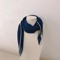 Detailopname van een donkerblauwe geplooide zijden sjaal met witte randen op een buste. - Donkerblauw