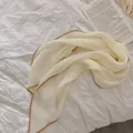 Gedetailleerd beeld van crème geplooide sjaal met een elegante gouden koordrand afwerking - Beige met camelkleurige rand