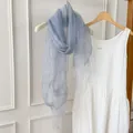 Detailed view of a light blue sheer scarf with tassels paired with a white dress background - 180cm / Light Blue