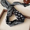 Primo piano di una sciarpa in seta nera con motivo paisley e floreale - Nero