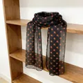 Elegant black sheer scarf with orange polka dots displayed on a rustic wooden shelf - Brown Orange Polka Dot