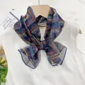 Elegant thin multi-colored patterned silk scarf tied in a bow on a white sleeveless top - Charming Geometry