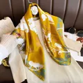 Detail view of a yellow silk square scarf with white floral print draped on a beige top - Golden Branches and Leaves