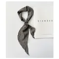 Close-up of a knotted gray-green ramie neck scarf displayed on a white magazine - 110cm / Gray