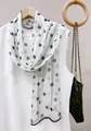 Elegant long white chiffon scarf with black polka dot pattern draped on a white top. - White Polka Dot