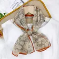 Elegant beige silk scarf streamer with black floral pattern and burnt orange borders - Camellia