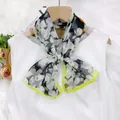 Lightweight floral chiffon scarf with lime green hem tied as a bow on a white dress - White Magnolia
