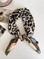 Vista dettagliata di un foulard di seta leopardato annodato su sfondo bianco minimalista - Border leopard print / 68cm