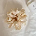 Detail van een beige parelmoer satijnen scrunchie met een elegante gelaagde structuur - Parelmoer Beige