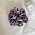 Gedetailleerde weergave van de paarse satijnen scrunchie met parelachtige laagjes. - Parelmoer Paars
