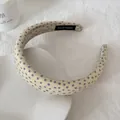 Detailopname van een crèmekleurige gaas hoofdband met paarse bloemmotieven en label - Haarband / 3 cm Breedte / Geel Bloemen
