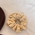 Gros plan détaillé d'un chouchou en maille crème avec de délicats pois noirs - Chouchou à Pois / Jaune