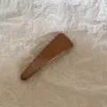 Gros plan d'une pince à cheveux BB triangulaire en tissu marron avec texture tissée - Triangulaire / Marron
