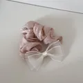 Detail van een roze satijnen scrunchie met hartjes en een witte organza strik - Roze Hart Strik Stijl