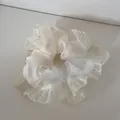 Detailaufnahme eines cremefarbenen Rüschen-Haargummis mit winzigen weißen Punkten - Beige Herz Gaze Stil
