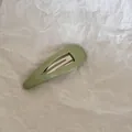 Vue détaillée d'une pince à cheveux en tissu vert sauge sur fond de papier froissé - Goutte d'Eau Évidée / Vert