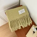 Close-up of sage green mohair scarf showing soft fuzzy texture and tassel fringe - Green