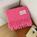 Gedetailleerd macrobeeld van een zachte roze mohair gebreide sjaal met kwastjes en kantlabel - Roze