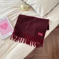 Detailed view of thick burgundy wool-blend scarf with soft tassels and woven label - 190cm / Cherry Red