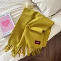 Close-up of a mustard yellow wool scarf with tassels on a bed - 190cm / Vegetable Yellow