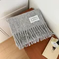 Close-up of a soft and cozy gray mohair knitted scarf with fringes and a lace brand patch - Gray