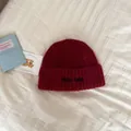 Close-up view of soft red knitted beanie hat featuring Hello Kele embroidery detail - One Size / Burgundy