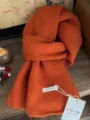 Detailansicht der weichen Strickstruktur des Schals aus 100% australischer Wolle. - Mittellanger Stil / Orange