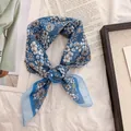 Close-up of a blue floral cotton-linen scarf tied in a stylish retro knot detail view - 58cm / Sunflowers